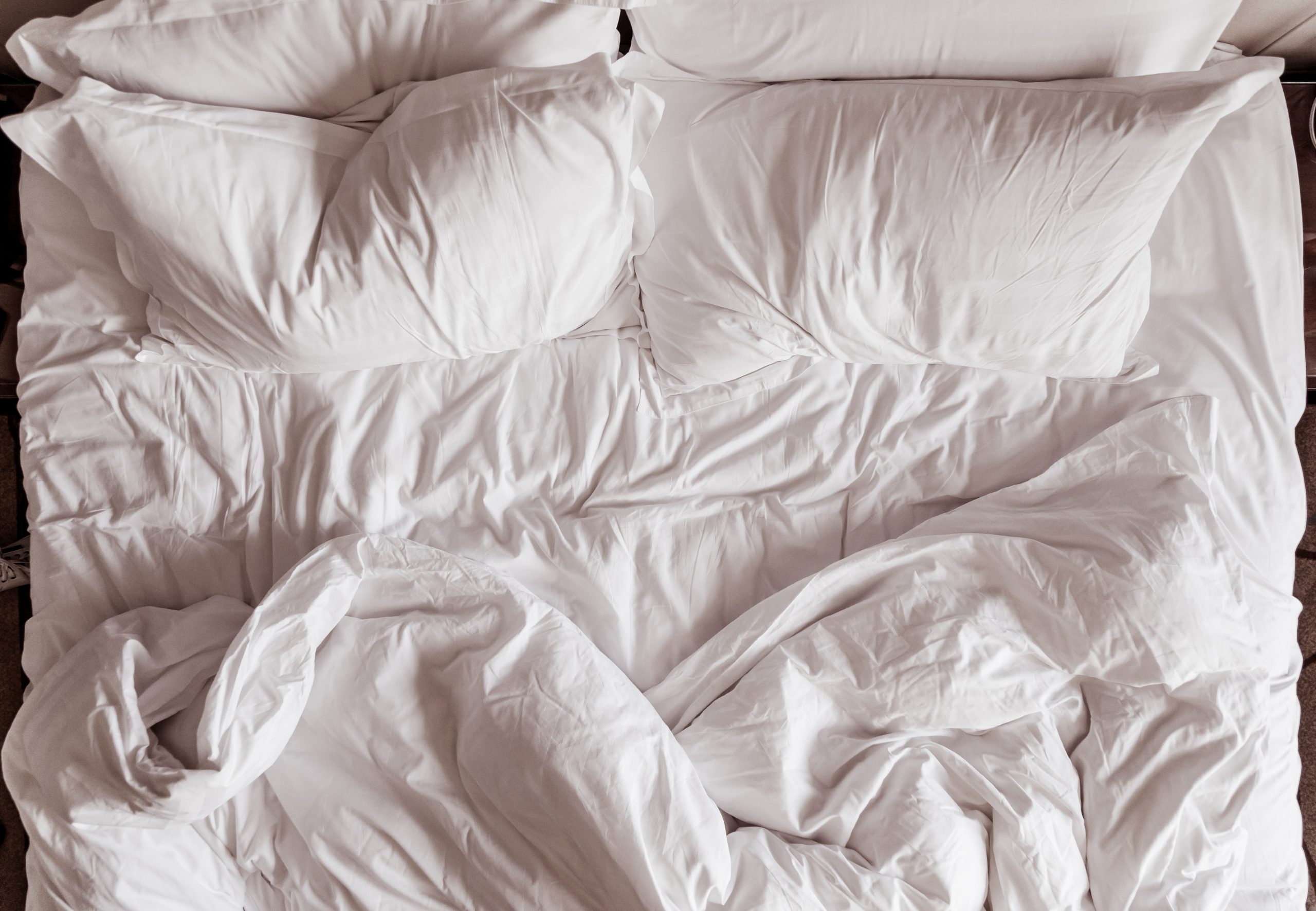 Смятая белая постель. Кровать вид сверху. Одеяло. Складки на одеяле. Постель вид сверху.